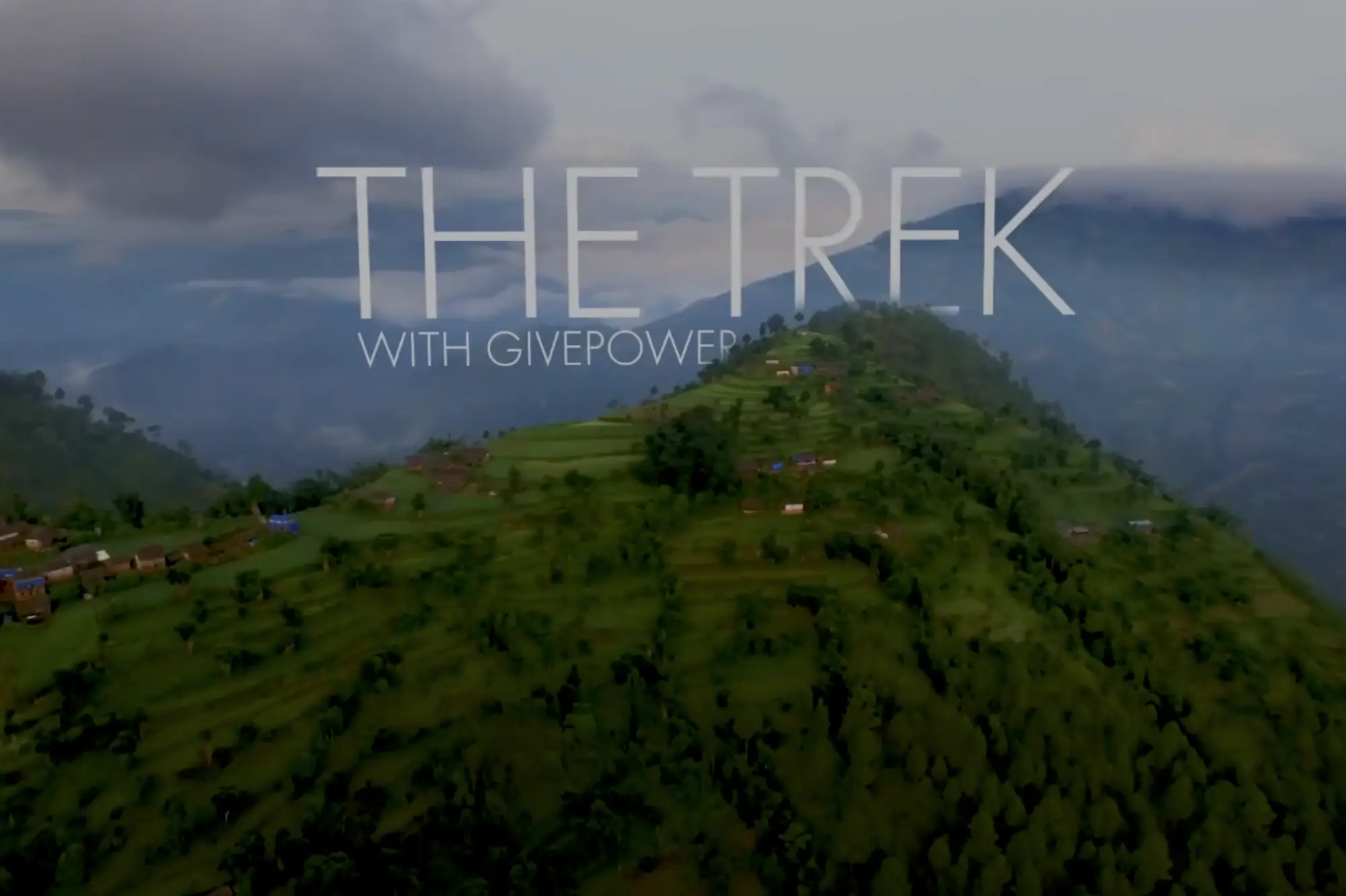 Vista aérea de un paisaje verde y montañoso con el texto «THE TREK WITH GIVEPOWER» superpuesto.