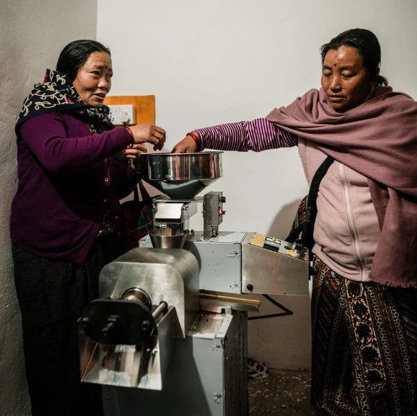 Two women use solar-powered food processing machine in Nepal.