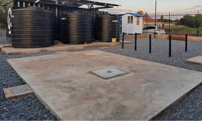 Concrete soak-pit slab with an access cover beside black water storage tanks