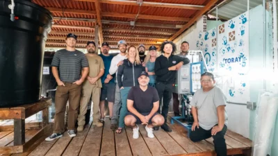 Once personas posan juntas dentro de un edificio rústico con tanques, tuberías y un sistema de agua de Toray.
